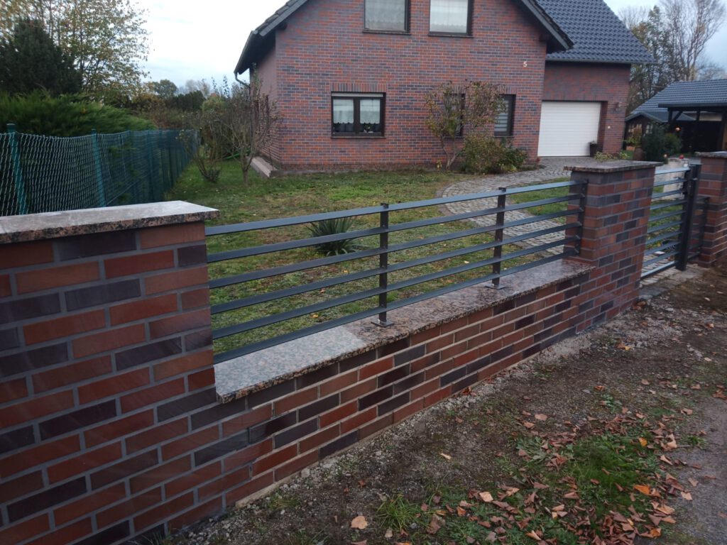 Flachstahlzaun aus Meisterhand eingefasst in gemauerte Säulen vor einem Klinkerhaus in Cottbus